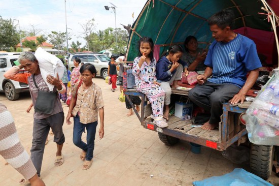 12月11日，在柬埔寨暹粒省一处居民安置点，人们领取救济物资后返回。新华社发（索万纳拉摄）