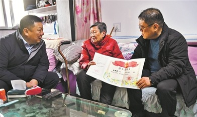 退役军人事务局工作人员为怀允英(中)送上其父的烈士证明书。张建军摄