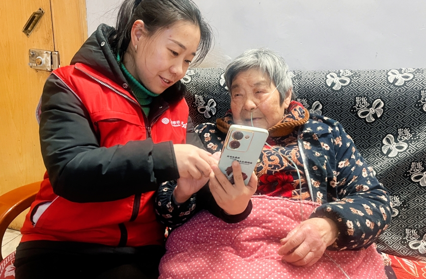 湖北移动志愿者正细心地教老人使用手机,暖心服务助“银发族”跨越数字鸿沟