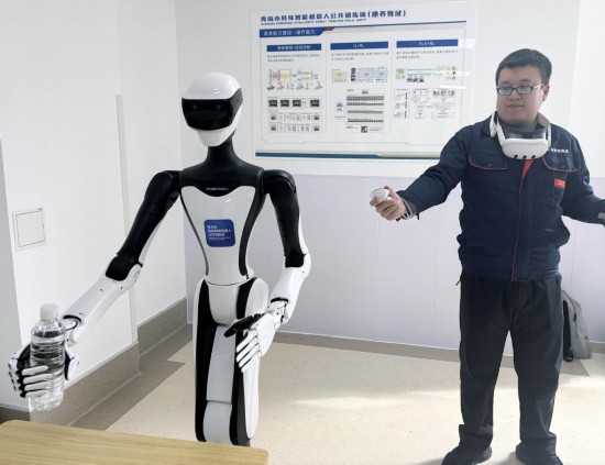 3月18日,一名训练师在青岛康养机器人训练验证中心指导机器人练习抓取物体(手机照片)。新华社发