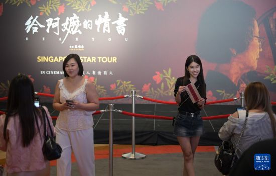 6月17日，人们在新加坡举行的电影《给阿嬷的情书》首映礼上与电影海报合影。新华社发（邓智炜摄）